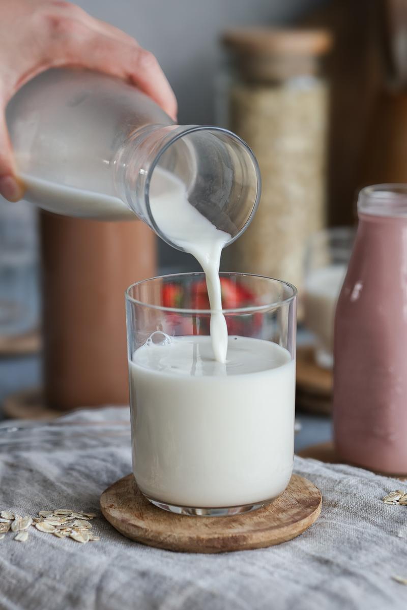 A vegan pouring dairy free and gluten free oatley into a glass