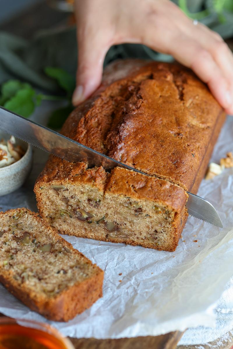 A vegetarian slicing the vegan zucchini bread into pieces to enjoy as an alternative to banana bread
