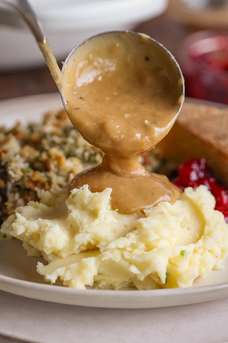 a plant-based person pouring the easy vegetarian gravy recipe on potato