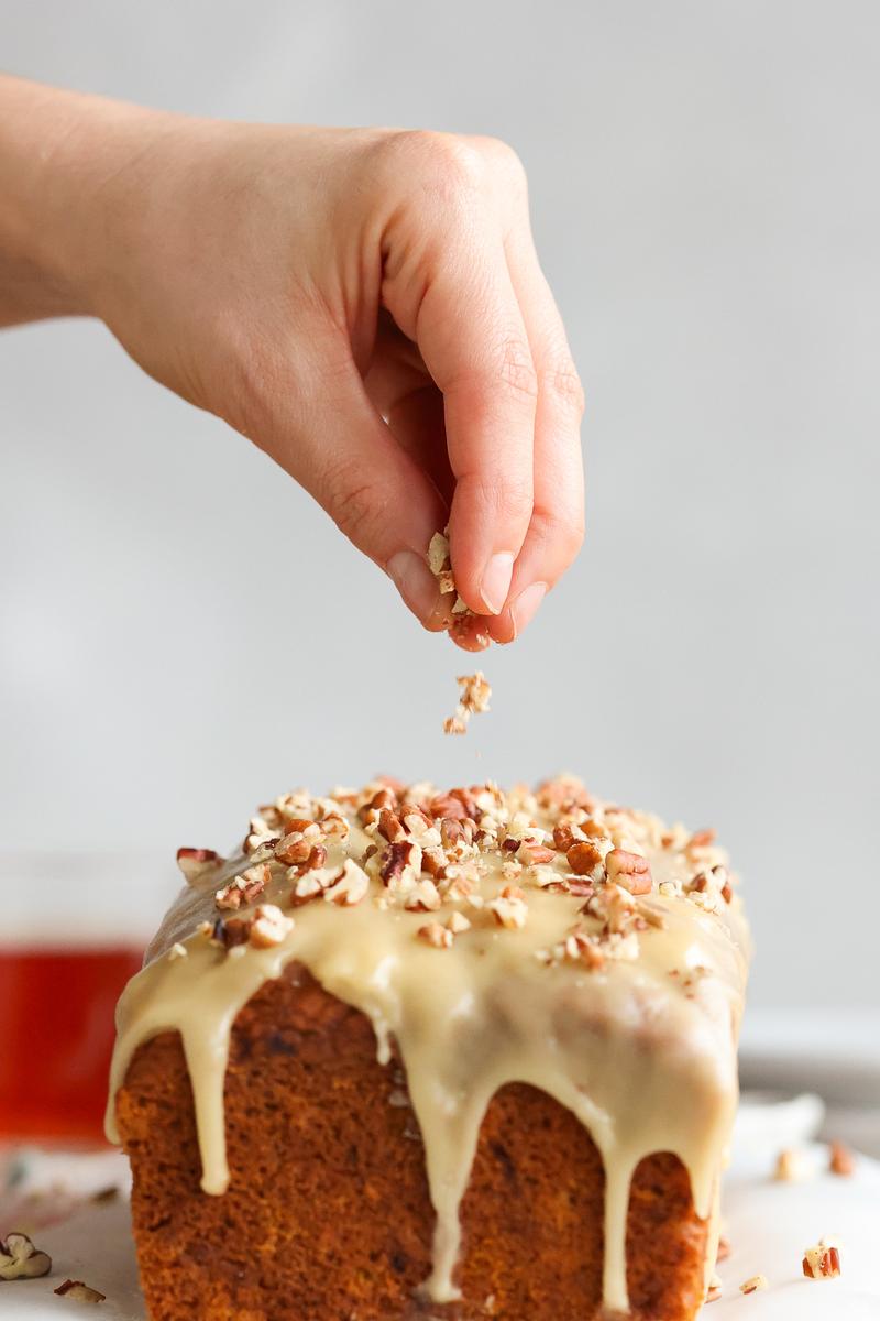 a no dairy chef sprinkling chopped pecans onto a cake for thanksgiving