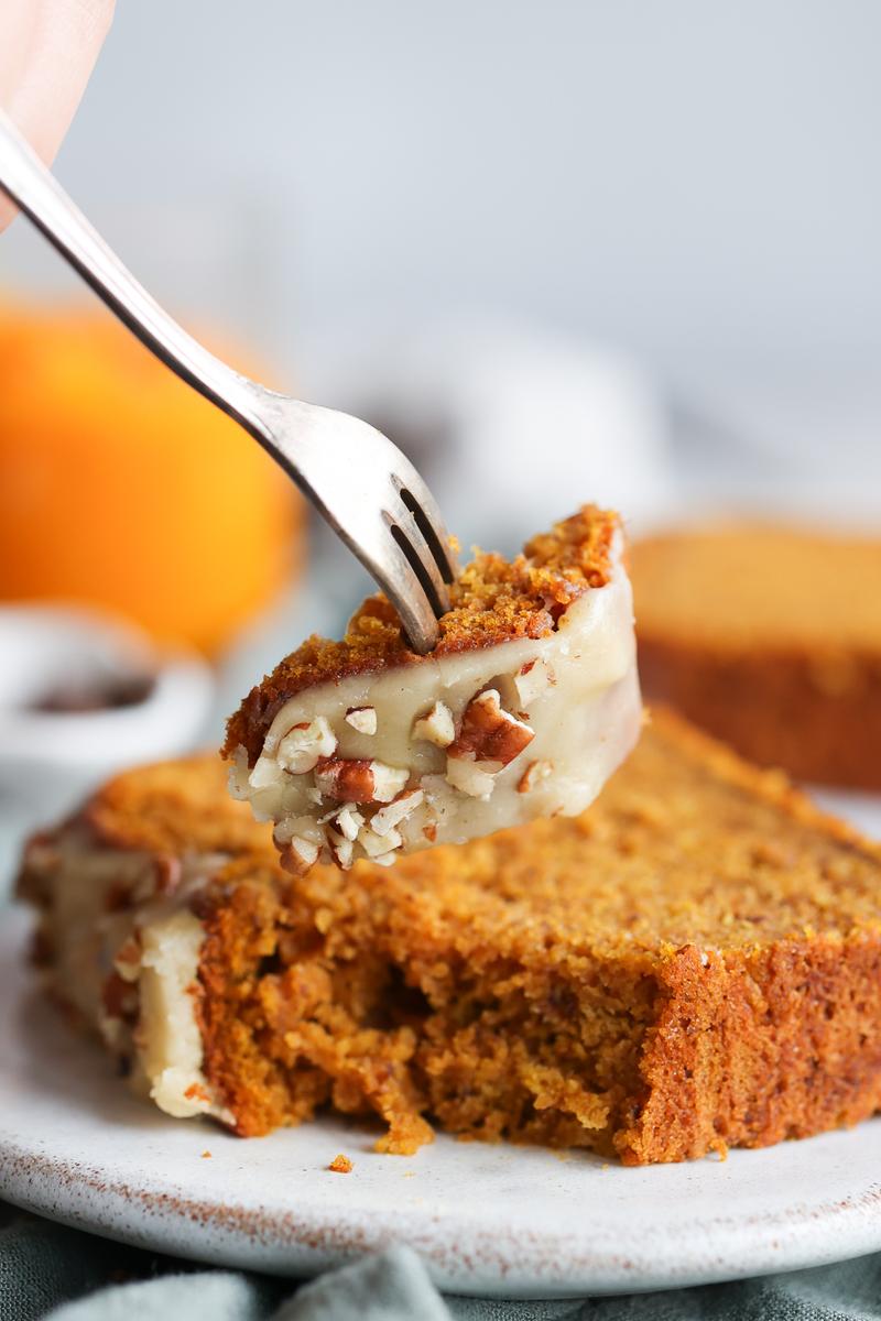 a vegetarian using a fork to lift a piece of banana loaf with pumpkins
