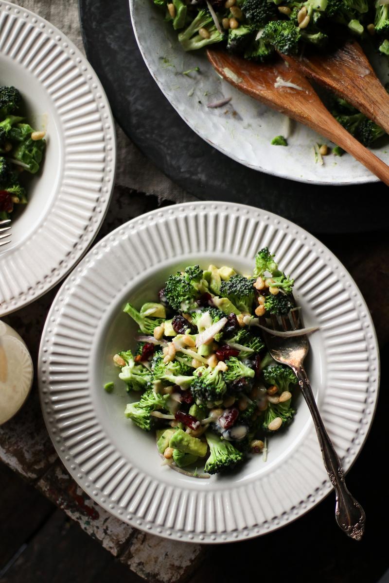 a bowl of salad with cranberries and broccoli